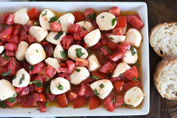 A white dish full of tomato mozzarella caprese salad.