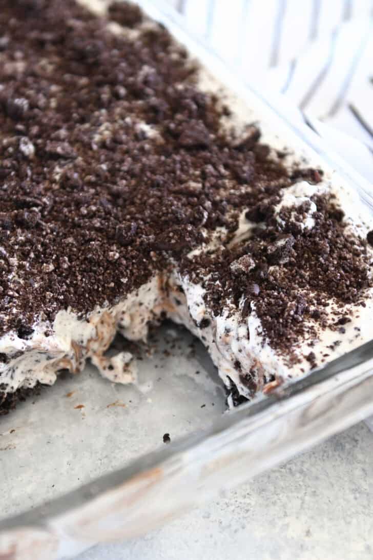 Glass pan of Oreo ice cream dessert with two squares taken out.