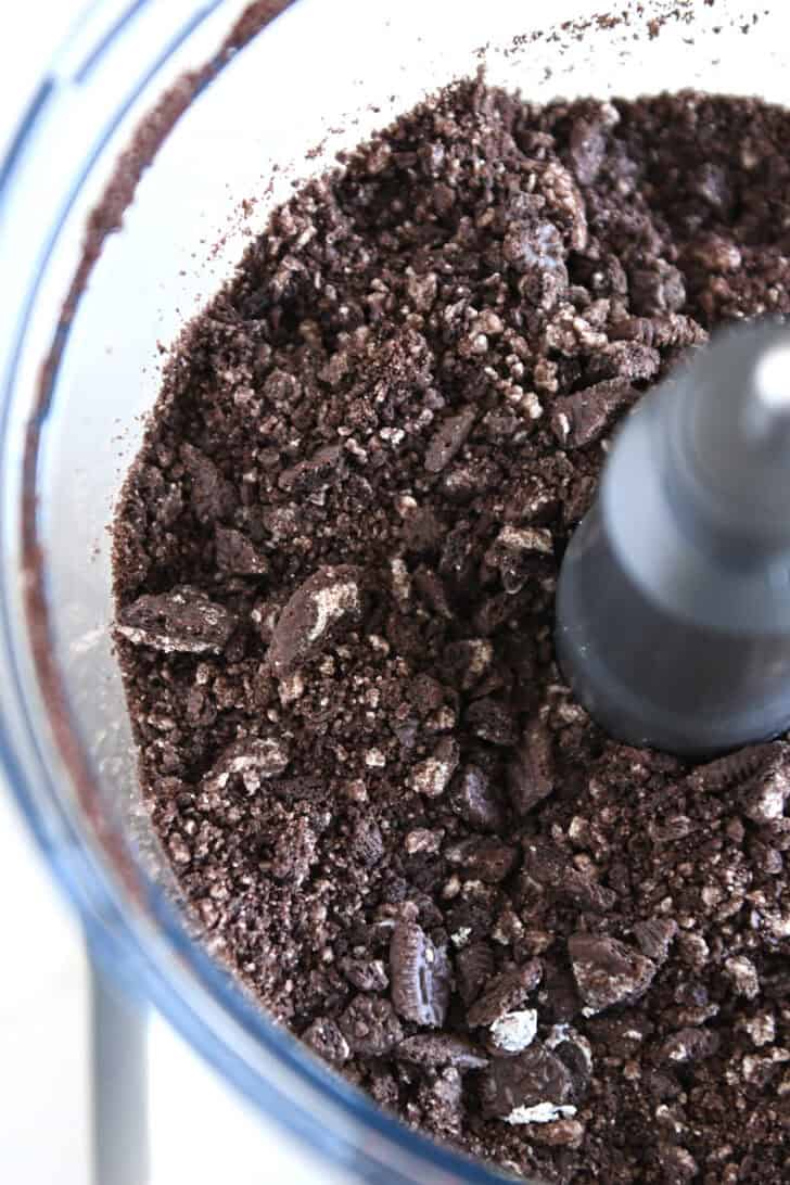Crushed Oreos in bowl of food processor.