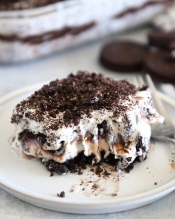 Square of layered Oreo ice cream dessert on gray plate with bite taken out.