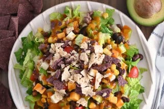 Top down view of White ridged plate with chopped taco salad and drizzled with homemade catalina dressing.