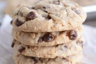 Stack of four baked cookies on wood board.