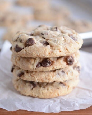 Stack of four baked cookies on wood board.