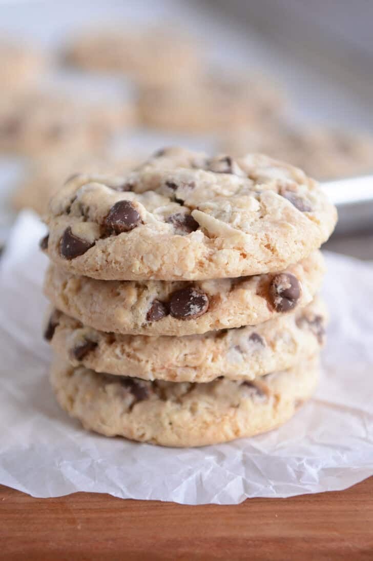 Stack of four baked cookies on wood board.