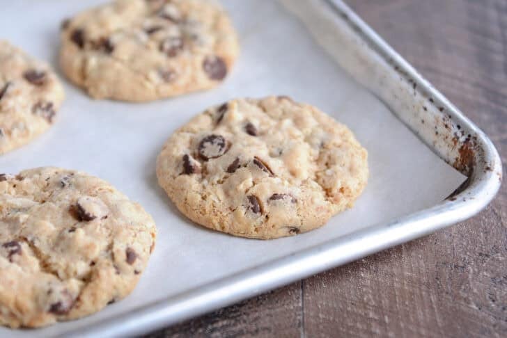 Baked chocolate chip coconut cookies on parchment lined baking sheet.