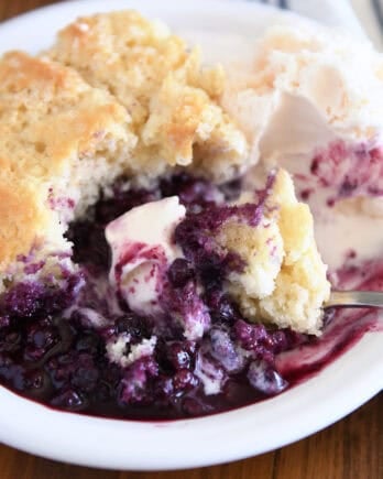 Triple berry cobbler on white plate with vanilla ice cream.