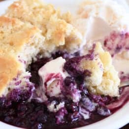 Triple berry cobbler on white plate with vanilla ice cream.