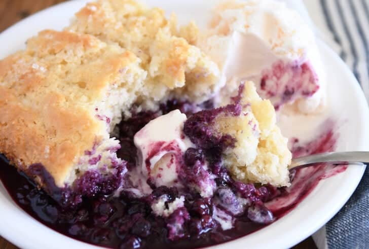 Triple berry cobbler on white plate with vanilla ice cream.