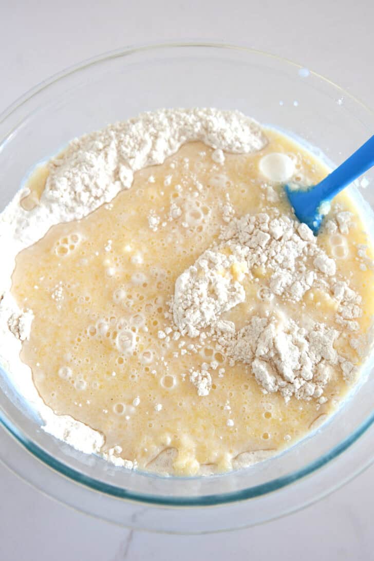 Dry ingredients mixed with wet ingredients for cobbler topping in glass bowl.