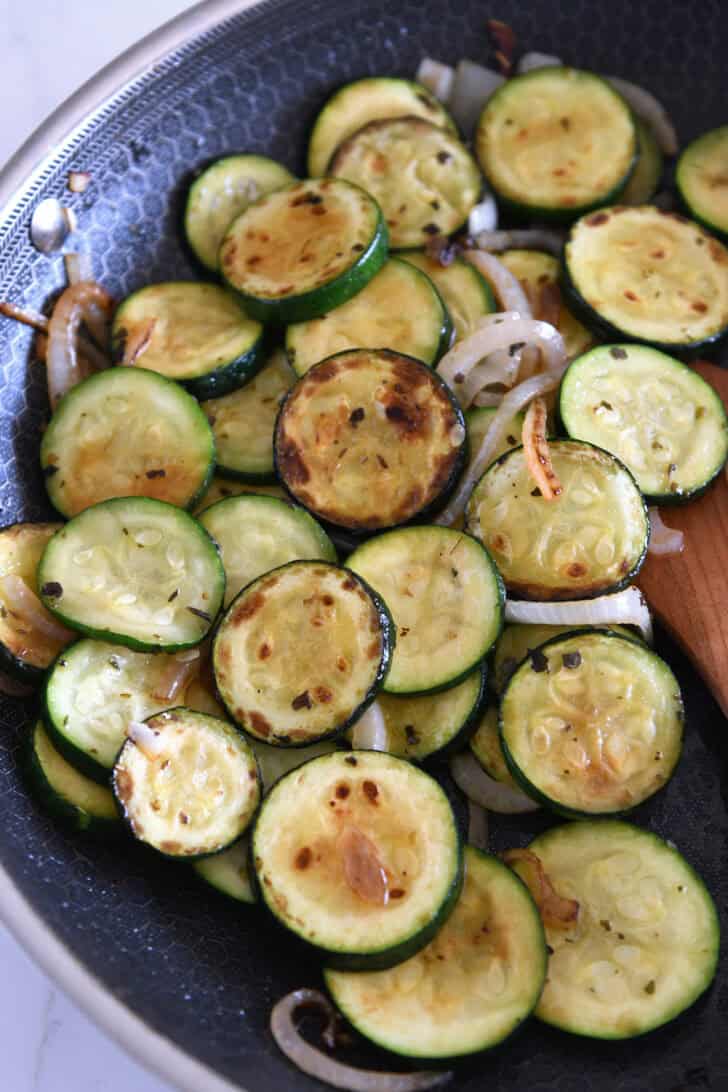 Top down view of a skillet of sautéed zucchini and onions.