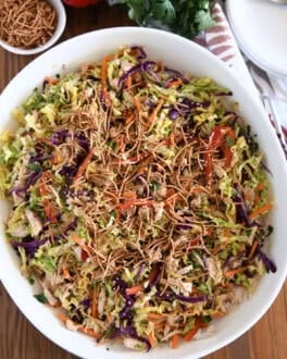 Asian chicken salad topped with chow mein noodles in white bowl.