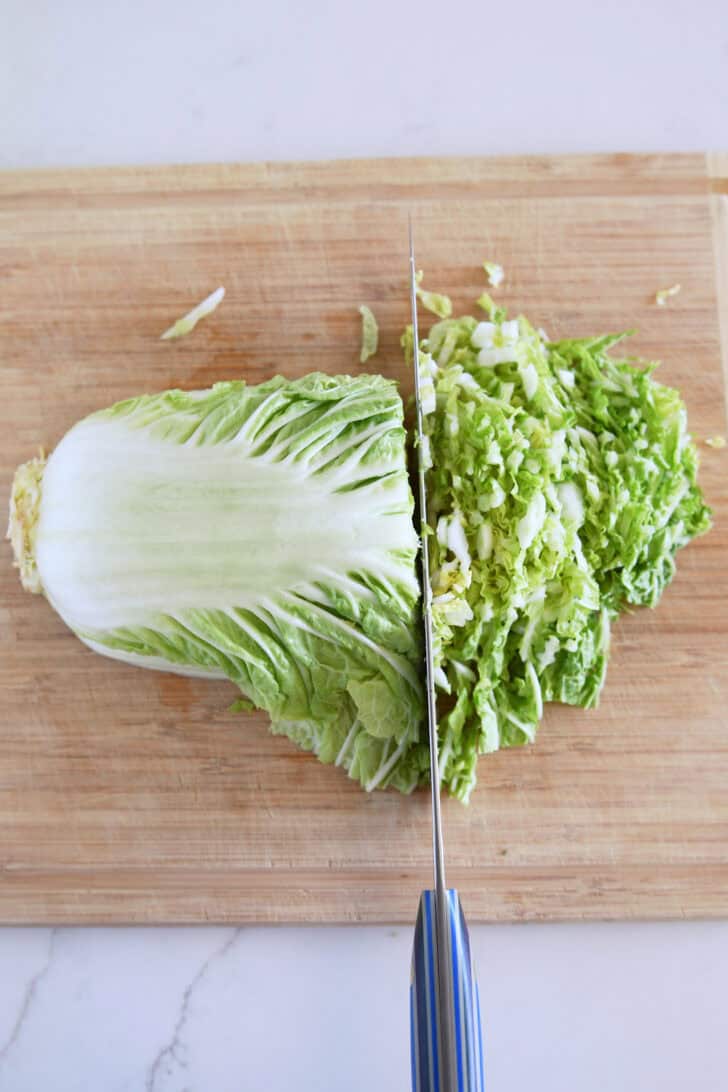 Napa cabbage thinly sliced on wood cutting board.