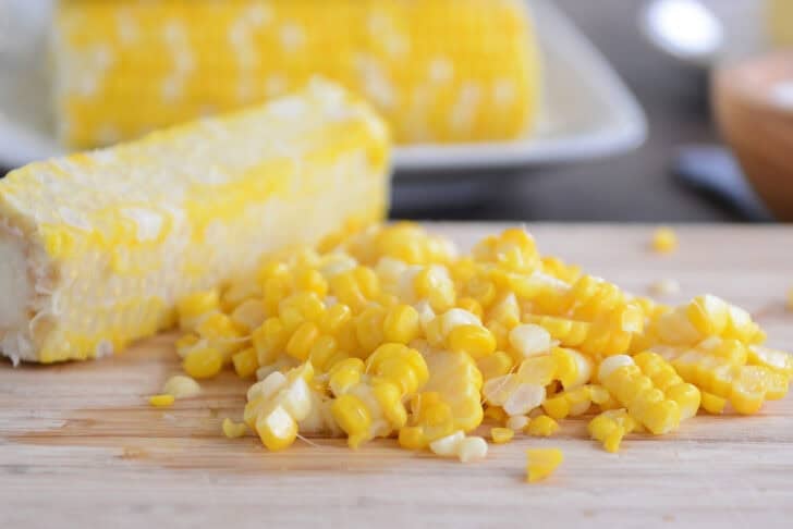 Kernels cut off the cob from fresh corn cob on wood cutting board