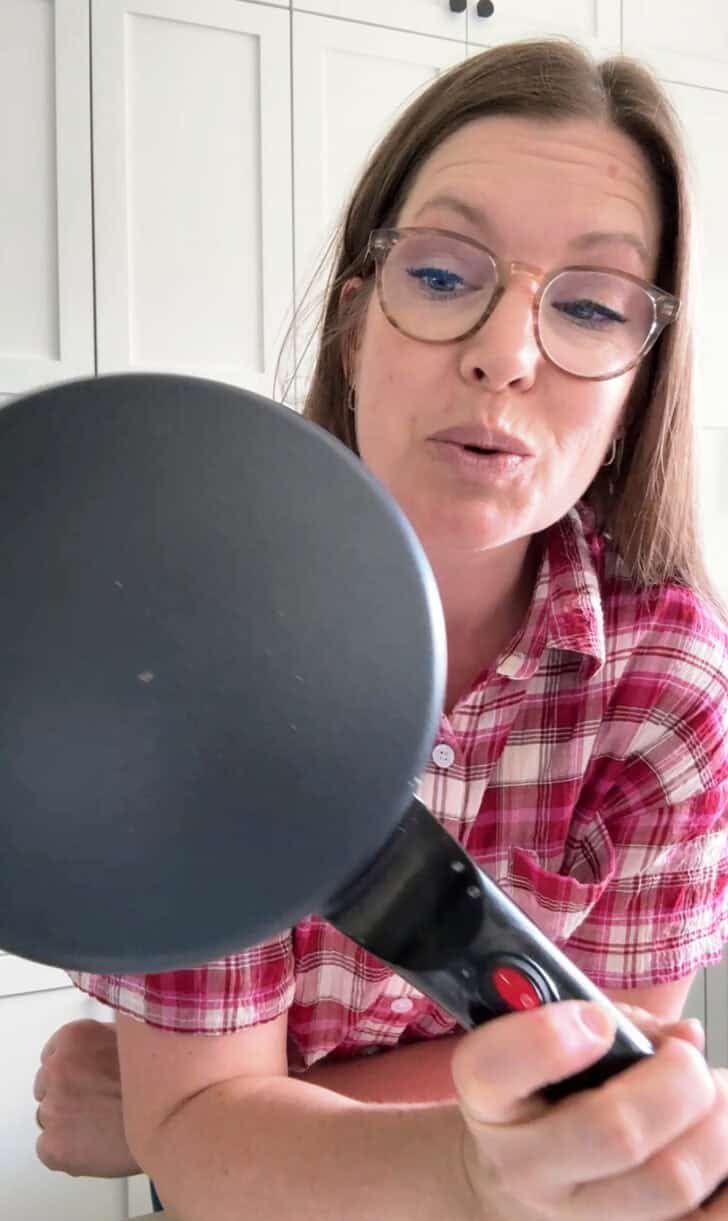Woman holding electric crepe maker.