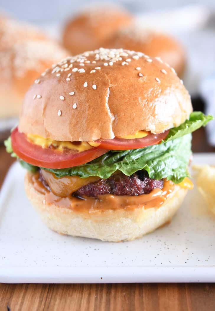 Homemade hamburger bun with juicy burger, lettuce, tomato and mustard.