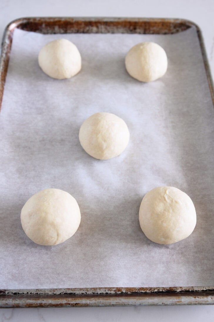 Round balls of dough on parchment lined baking sheet.