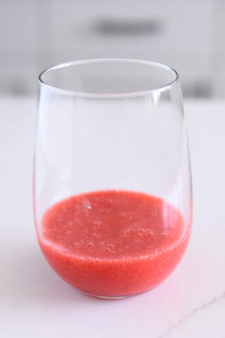 Glass cup with 1-inch of strawberry puree poured in the bottom.