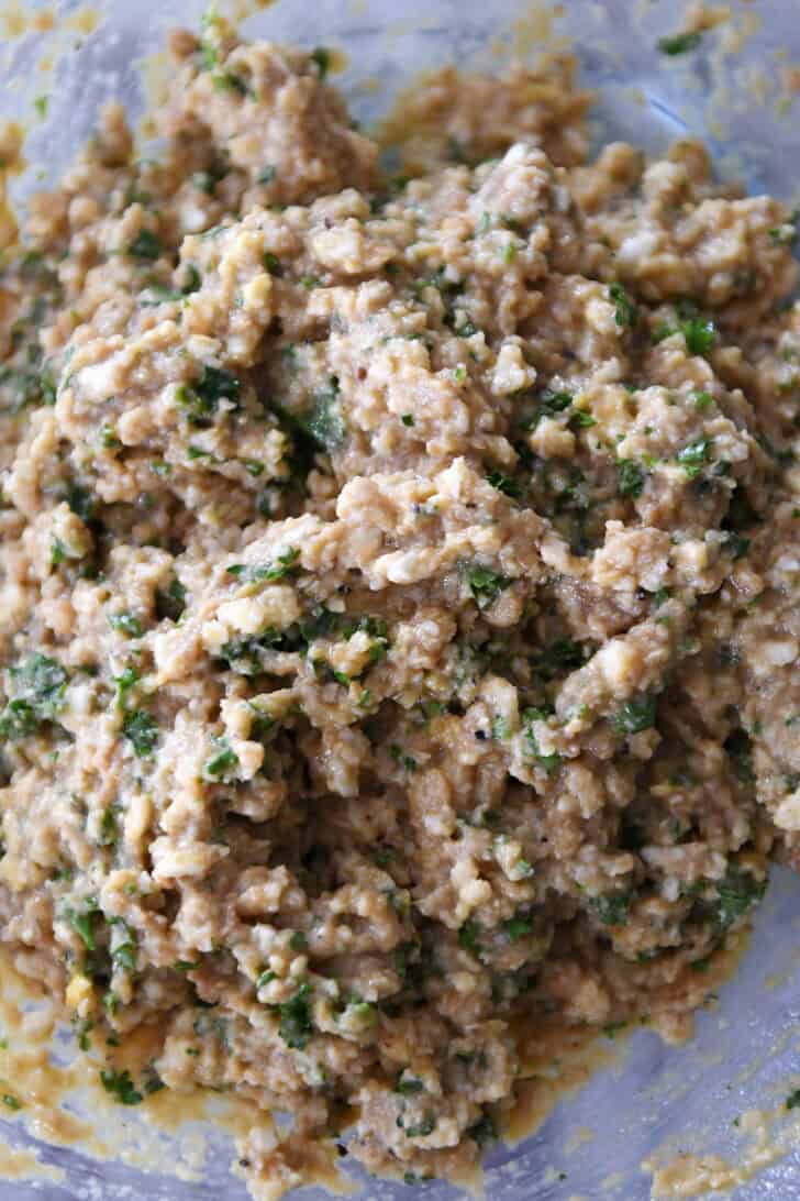 Top down view of a wet bread crumb and spice mixture in a glass bowl.