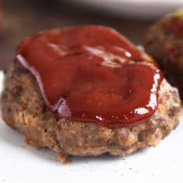 A glazed mini meatloaf on a white platter.