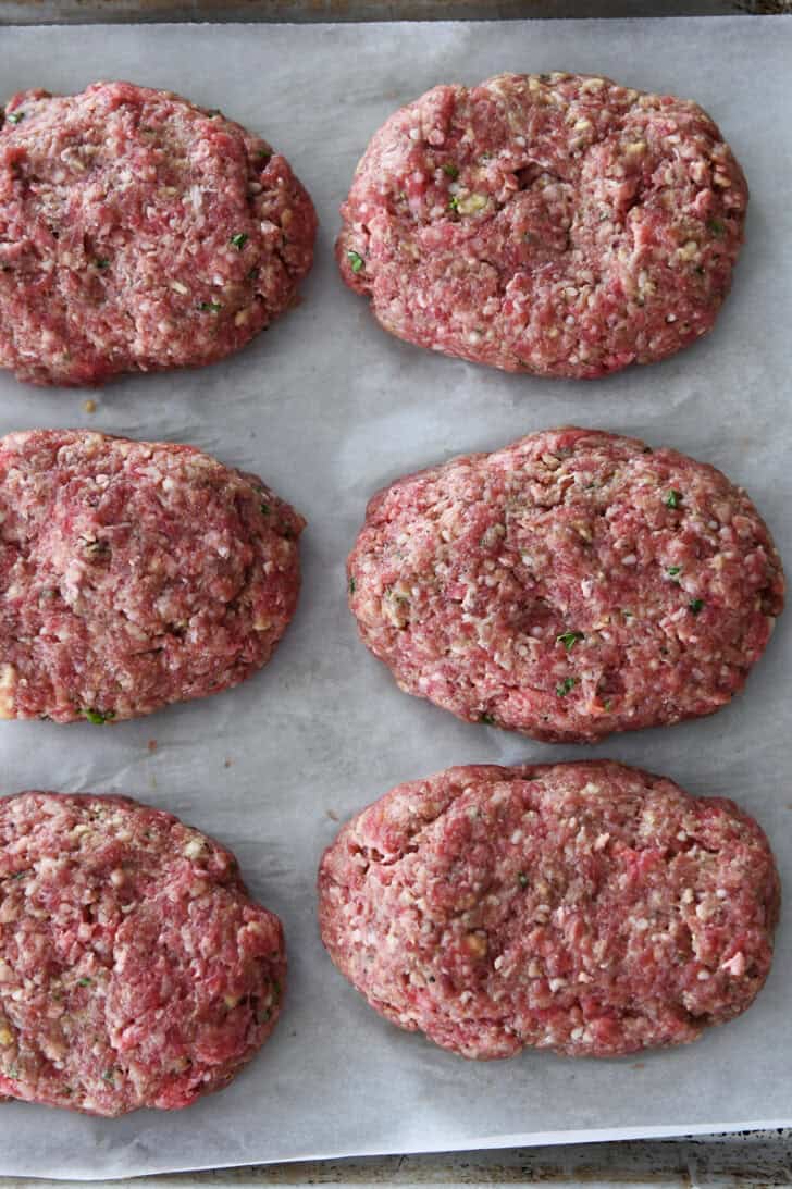 Top down view of raw mini meatloaves on a piece of parchment.