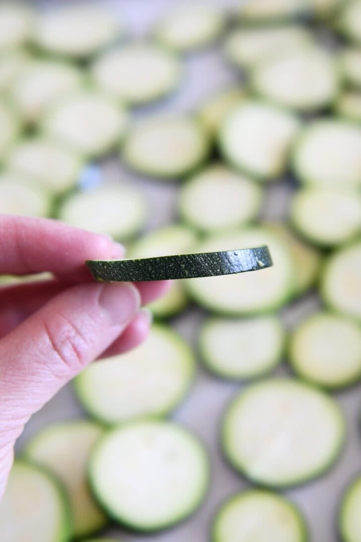 Holding thinly sliced zucchini.