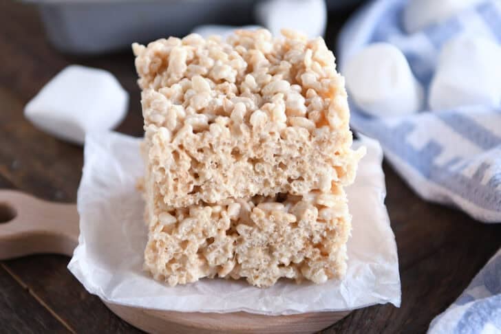 Two rice krispie treats stacked on top of each other on a piece of parchemtn paper.