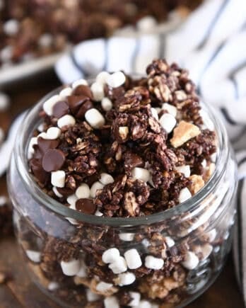 Glass jar filled with chocolate granola, graham cracker pieces and mini marshmallows.