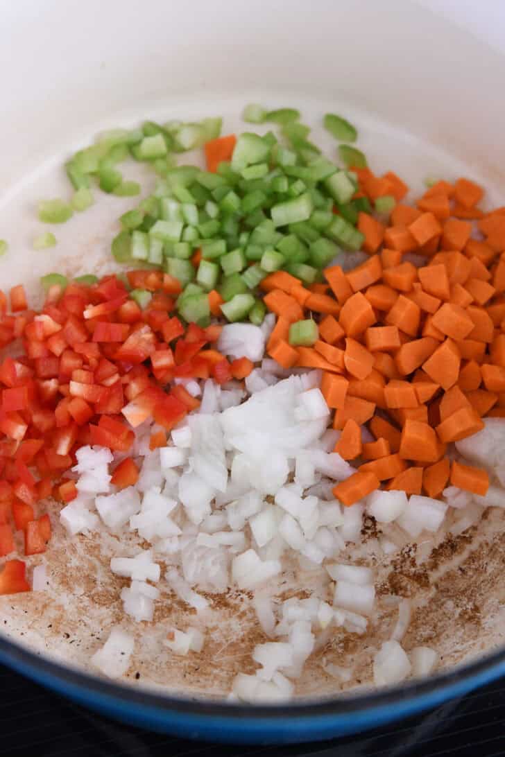 Dutch oven pot with red bell peppers, celery, carrots, and onions.