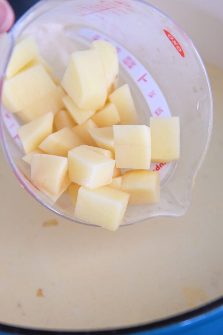 Adding diced Yukon gold potatoes to pot with chowder.