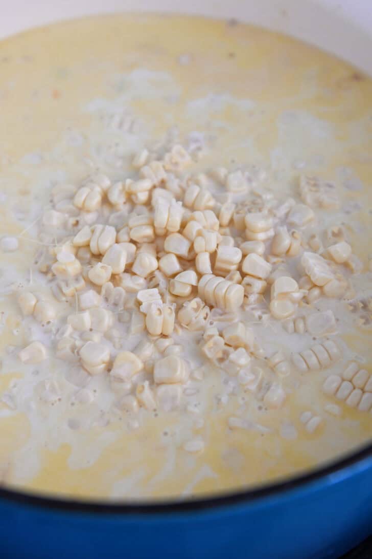 Fresh corn kernels in dutch oven pot with creamy chowder ingredients.