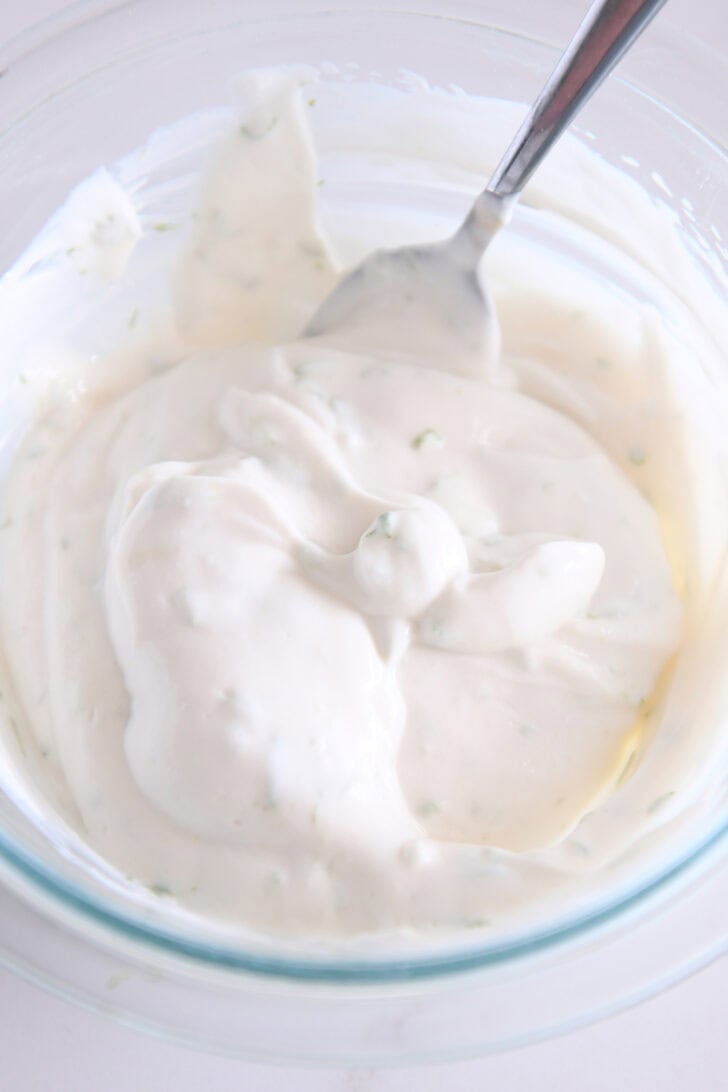 Glass bowl with creamy watermelon dip and spoon.