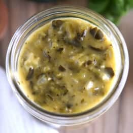 Top view of a glass jar filled with green enchilada sauce.