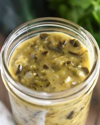 Top down view of a glass jar filled with green enchilada sauce.