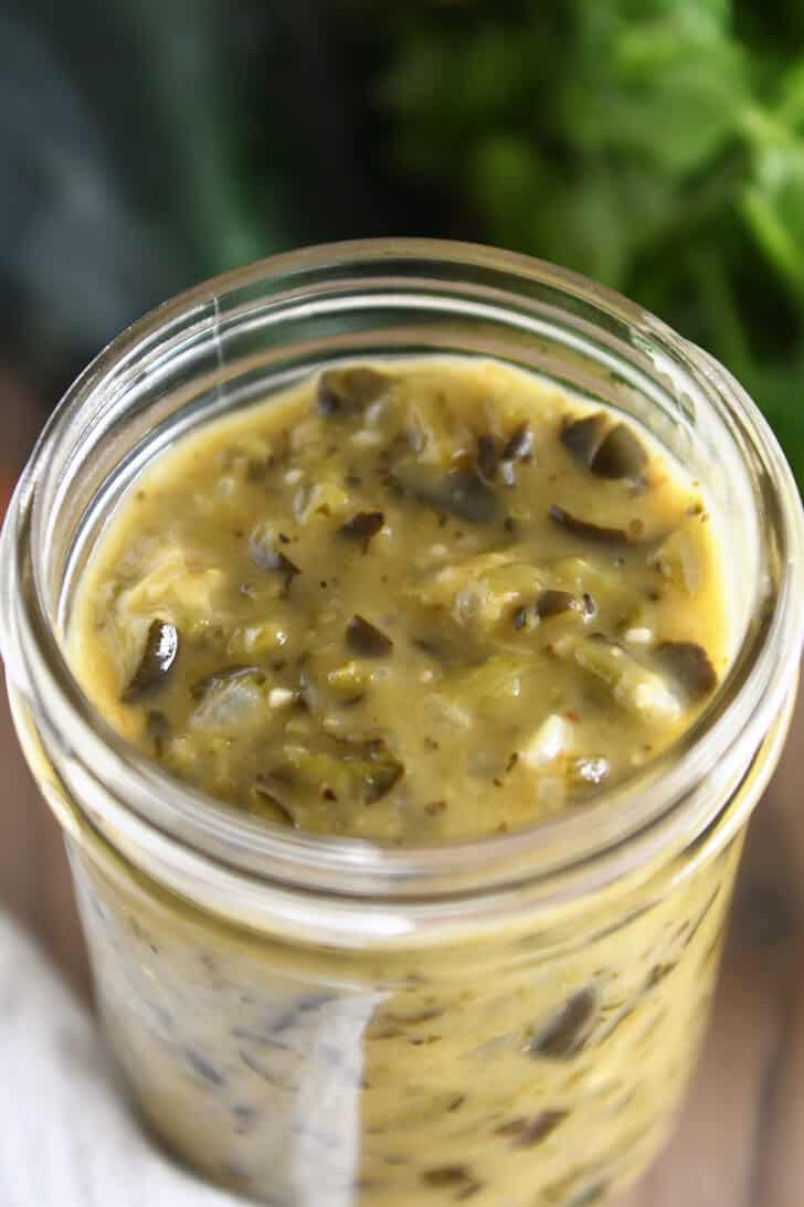 Top down view of a glass jar filled with green enchilada sauce.