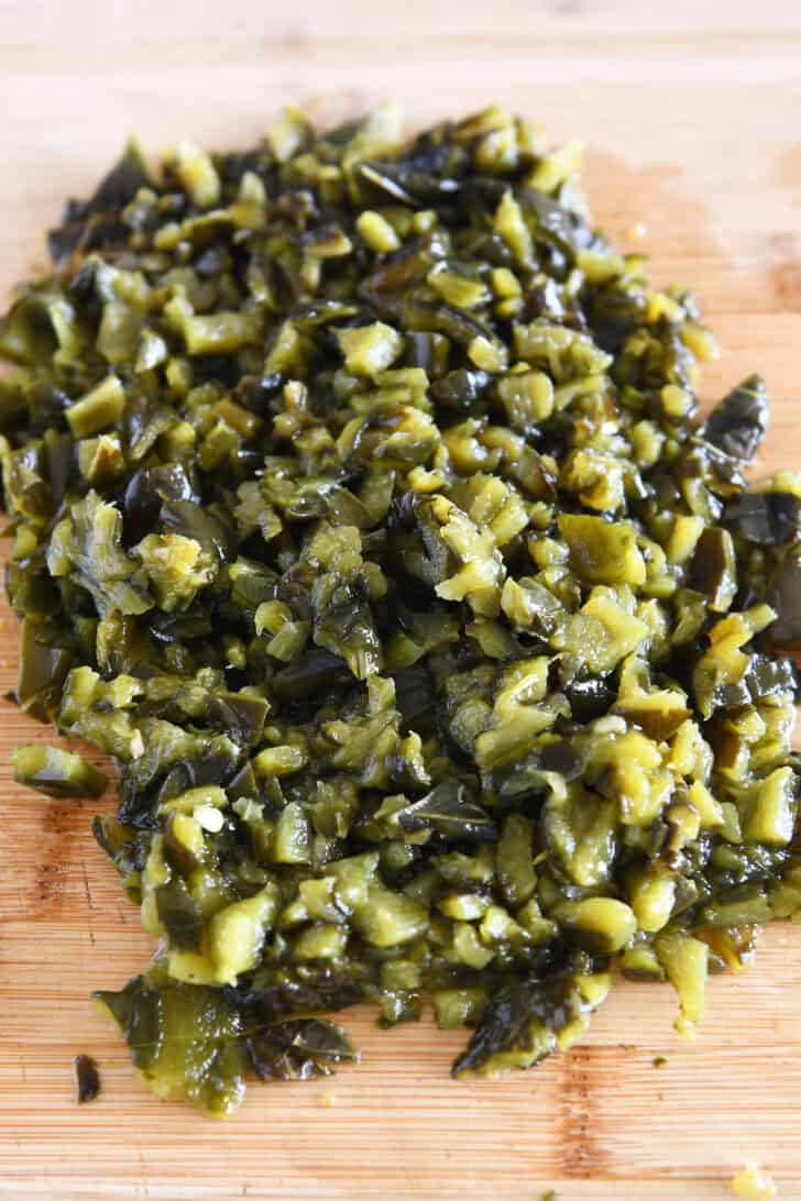 Top down view of a cutting board with chopped roasted green peppers.