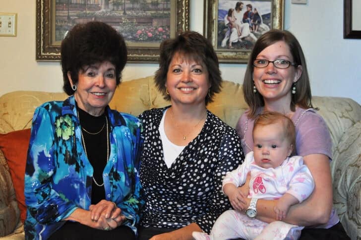 Grandmother, mother, daughter and child on tan couch.