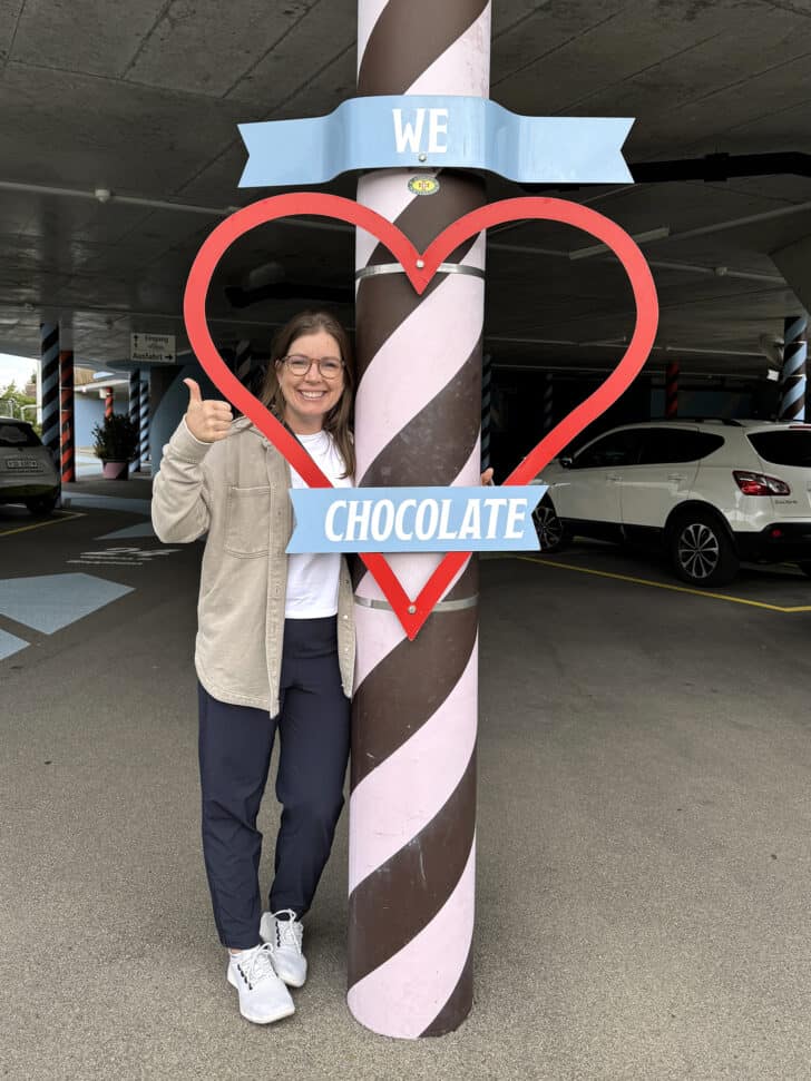 Mel standing in front of a "We love chocolate" sign.