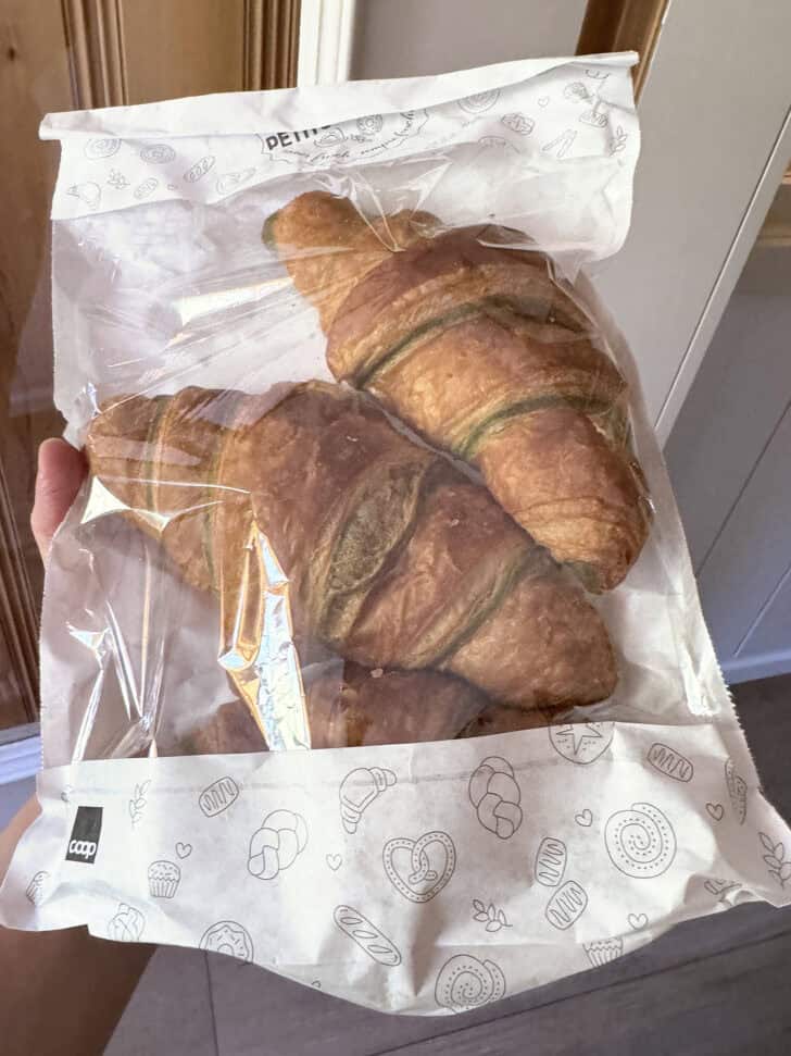 Three pistachio croissants in cellophane bag.