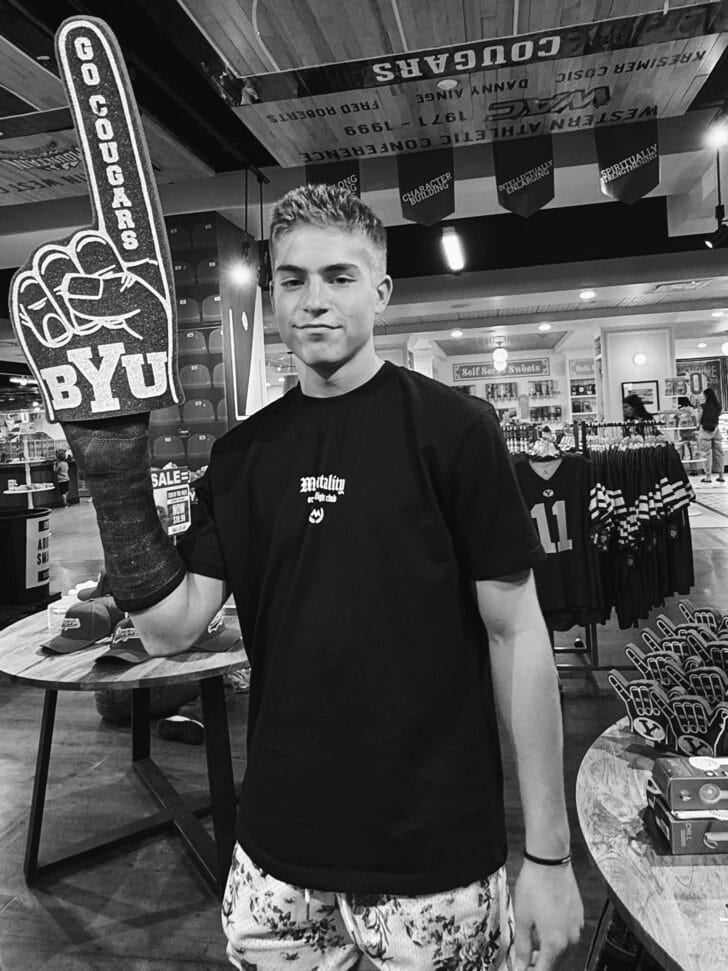 Black and white photo of young man holding foam finger in hand with cast.