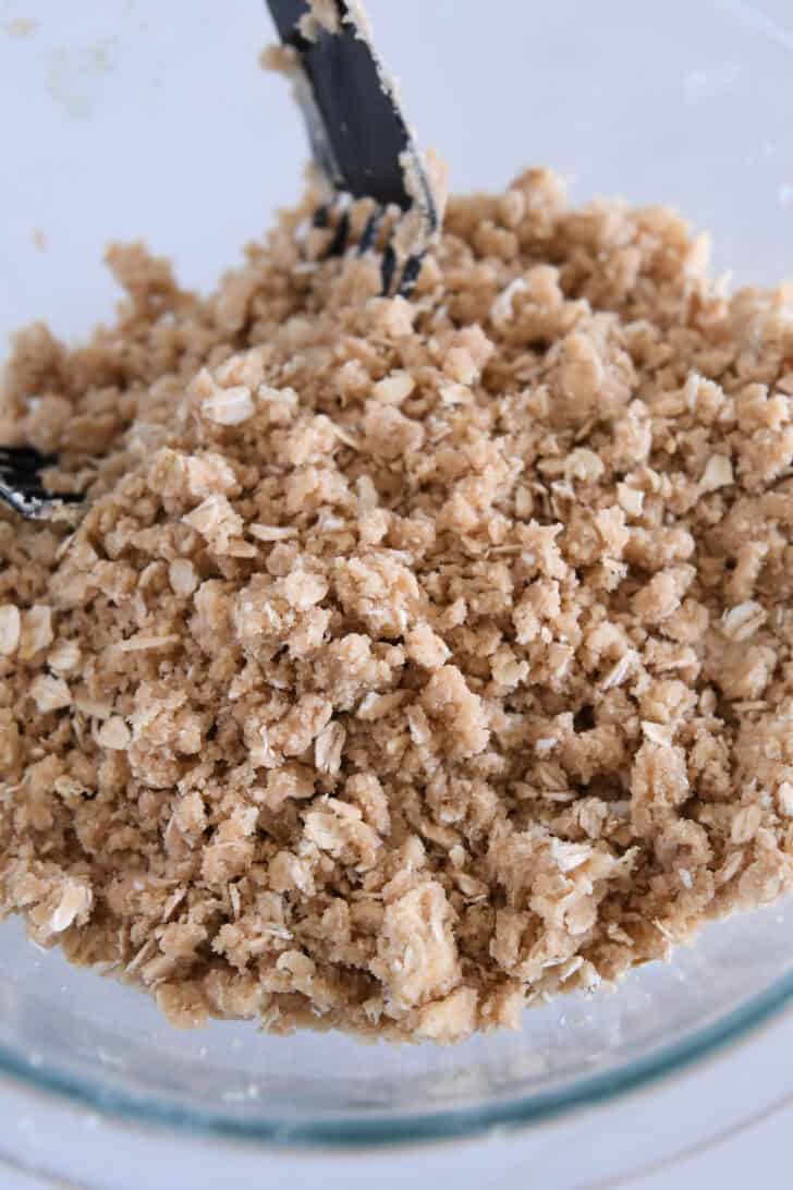 Crumbly mixture of flour, brown sugar, butter and oats in glass bowl.