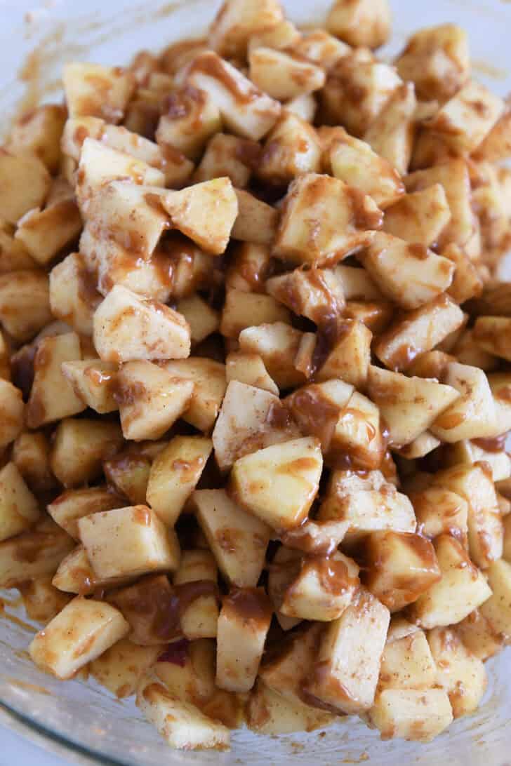 Glass bowl with chopped apples and caramel sauce.