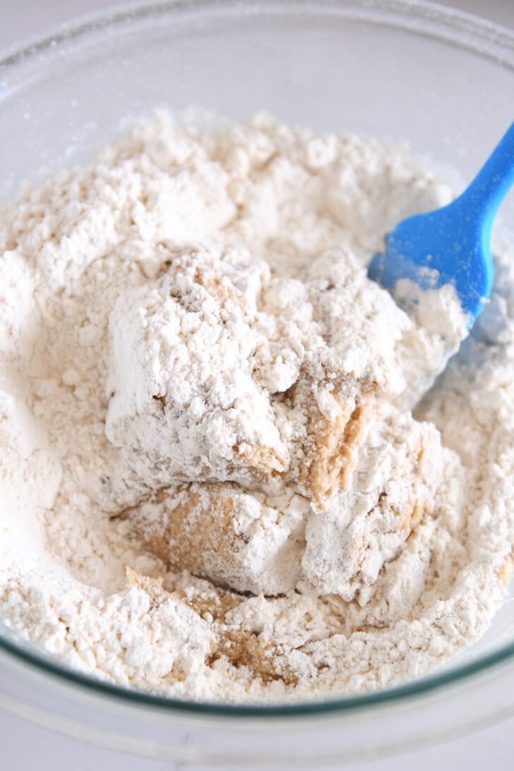 A glass bowls with flour getting mixed into cooke dough.
