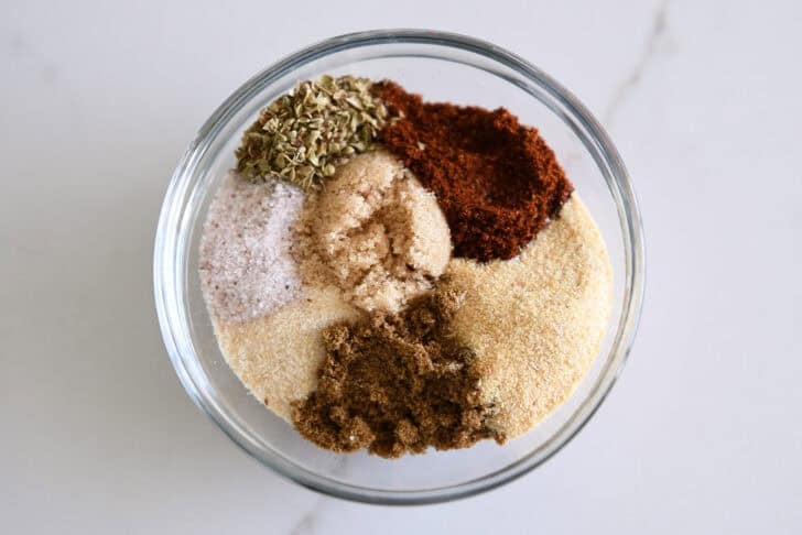Small glass bowl with chili powder, onion powder, garlic powder, ground cumin, dried oregano, salt and brown sugar.