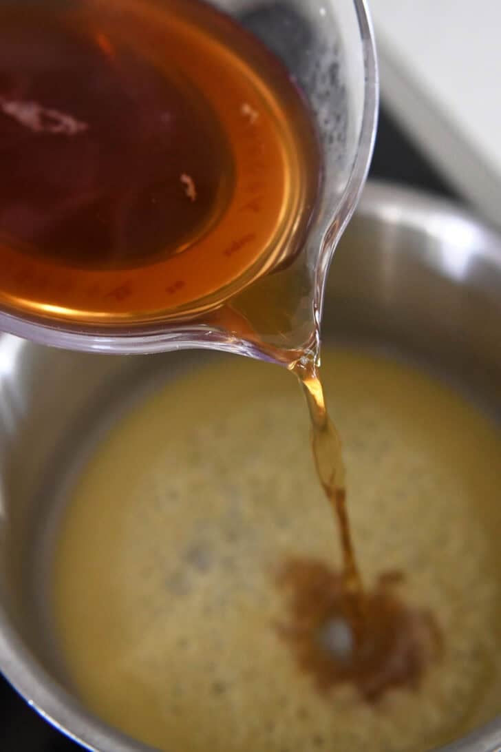 Pouring beef broth into pan with roux made from olive oil and flour.