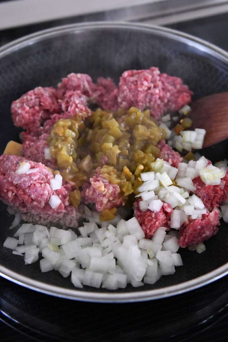 Ground beef, onions, and green chiles cooking in 12-inch nonstick skillet on induction stovetop.