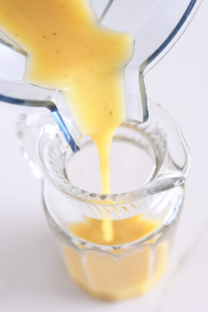 Pouring apple cider vinaigrette into glass jar.