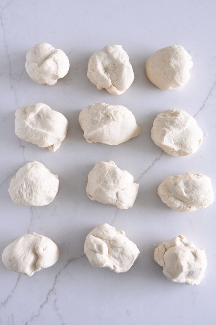 Dough split into 12 pieces on white counter.
