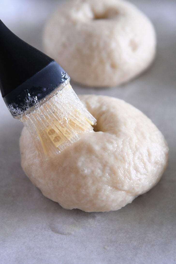 Brushing boiled bagel with egg wash.