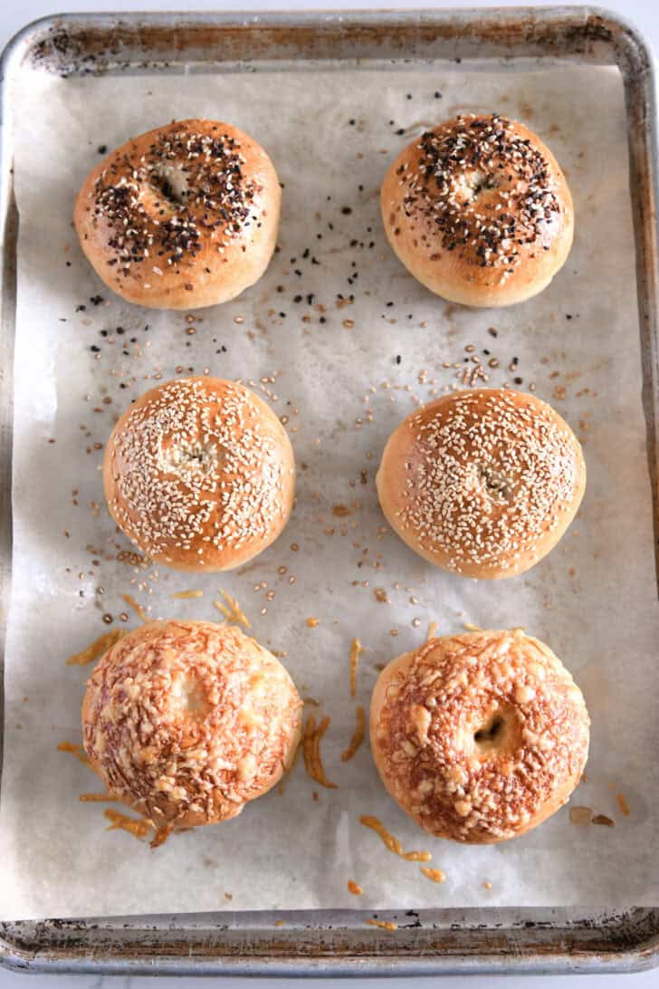 Top down view of six baked bagels on half sheet pan.