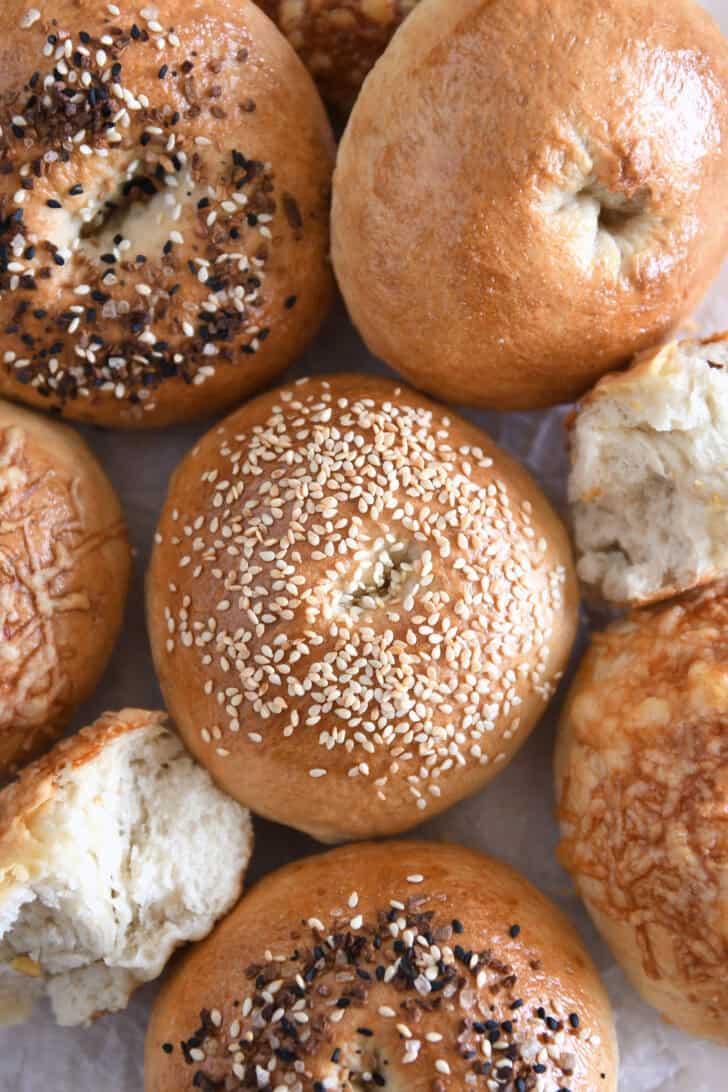 Top down view of sesame seed topped bagel with several other baked bagels.